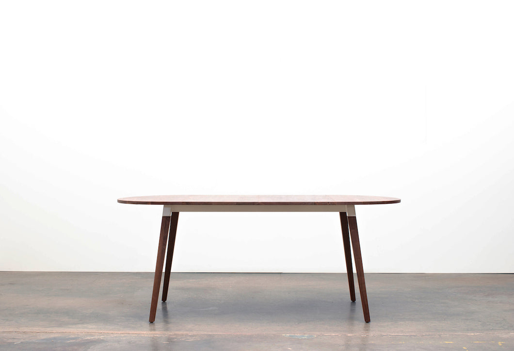 Minimalist Modern Dining Table with Angled Legs. Handmade of Solid Wood and Powder Coated Metal. Available in Walnut, Oak or Ash with Oval or Rectangular Top. Custom Paint Colors Available.